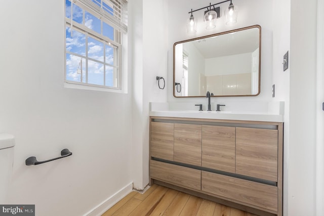 bathroom with vanity, toilet, and hardwood / wood-style floors