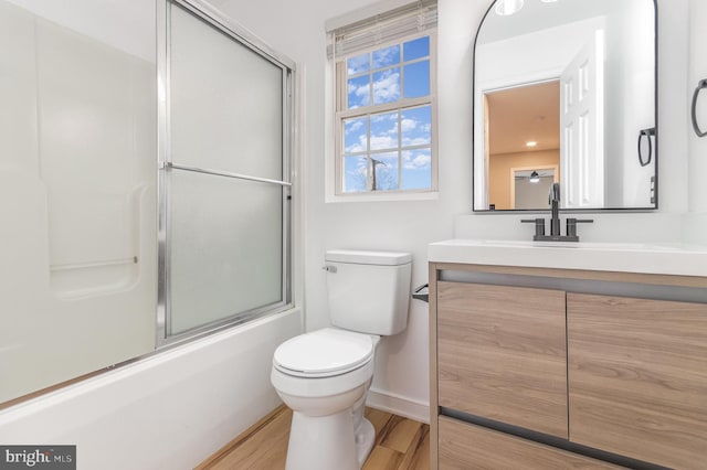 full bathroom featuring hardwood / wood-style flooring, vanity, toilet, and combined bath / shower with glass door