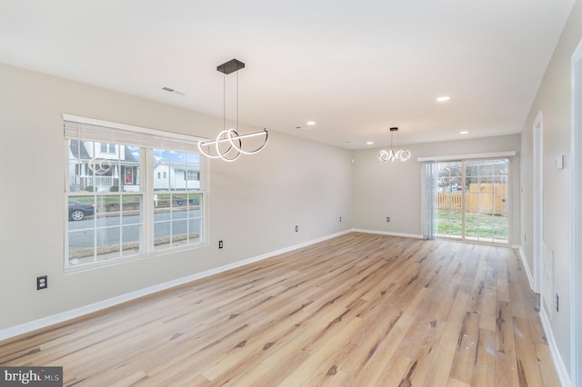 unfurnished dining area with a chandelier and light hardwood / wood-style flooring