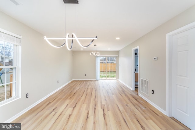 unfurnished dining area with a chandelier and light hardwood / wood-style flooring