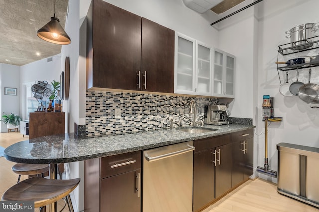 kitchen featuring dark brown cabinetry, dishwasher, sink, and dark stone counters