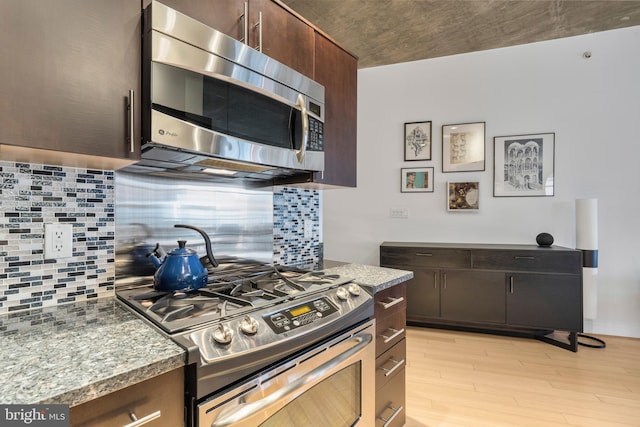 kitchen with decorative backsplash, dark brown cabinetry, stainless steel appliances, light stone countertops, and light hardwood / wood-style flooring