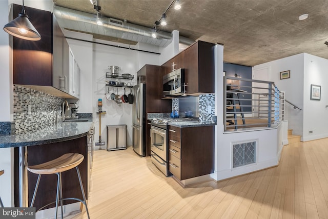 kitchen with sink, dark brown cabinets, light wood-type flooring, appliances with stainless steel finishes, and pendant lighting