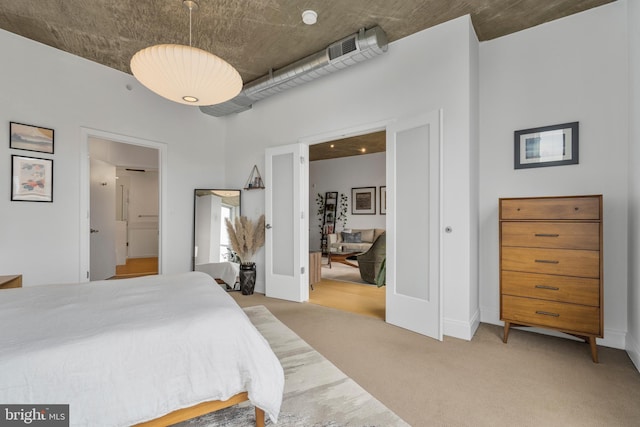 bedroom with connected bathroom, light colored carpet, and french doors