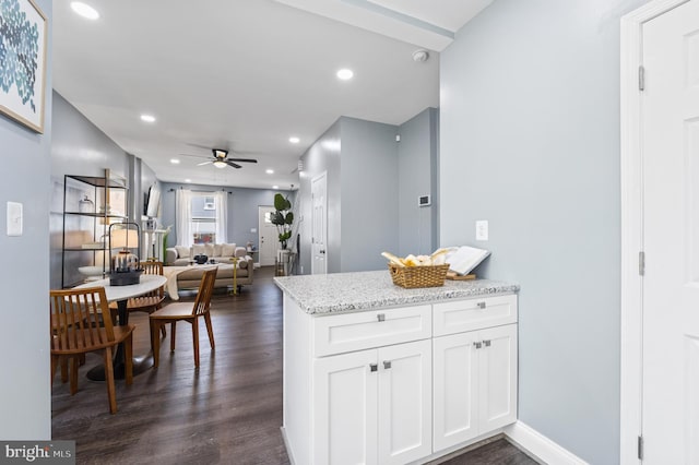 kitchen featuring white cabinetry, light stone counters, dark wood-type flooring, and ceiling fan