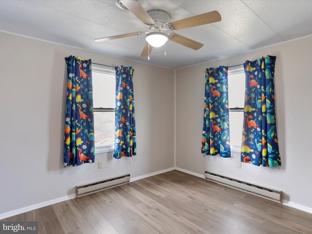 spare room featuring ceiling fan, light hardwood / wood-style floors, a textured ceiling, and a baseboard heating unit