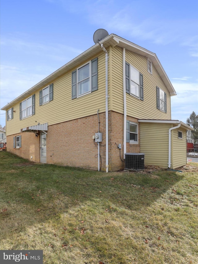 back of property featuring cooling unit and a yard