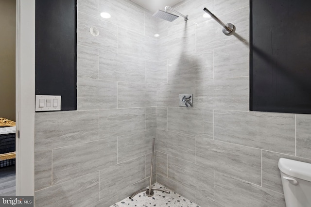 bathroom featuring a tile shower and toilet