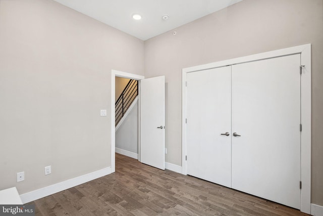 unfurnished bedroom featuring a closet, baseboards, and wood finished floors