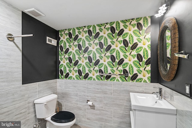 bathroom with toilet, vanity, visible vents, and tile walls