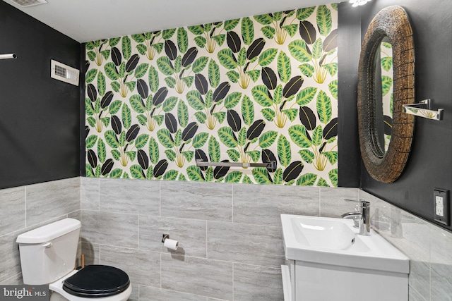 bathroom with visible vents, tile walls, toilet, and vanity