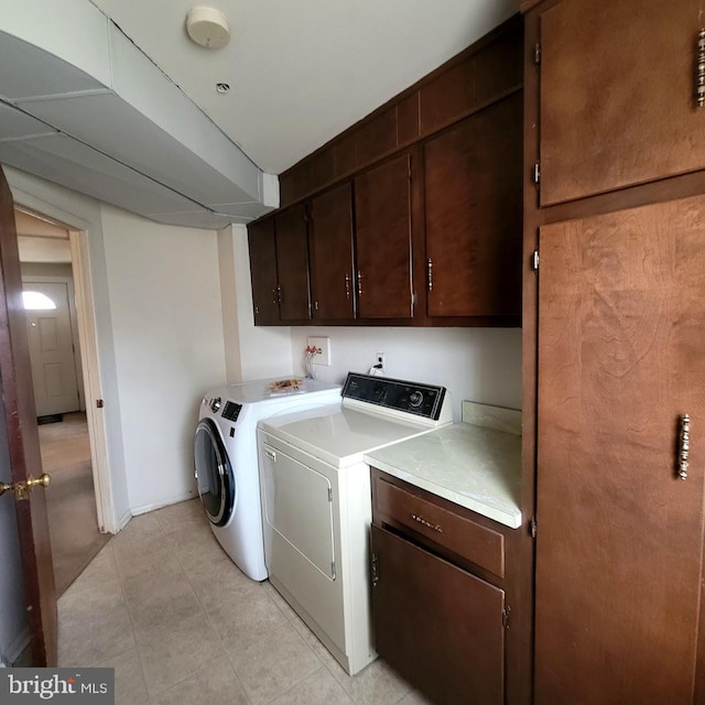 laundry room featuring cabinets, separate washer and dryer, and light tile patterned floors