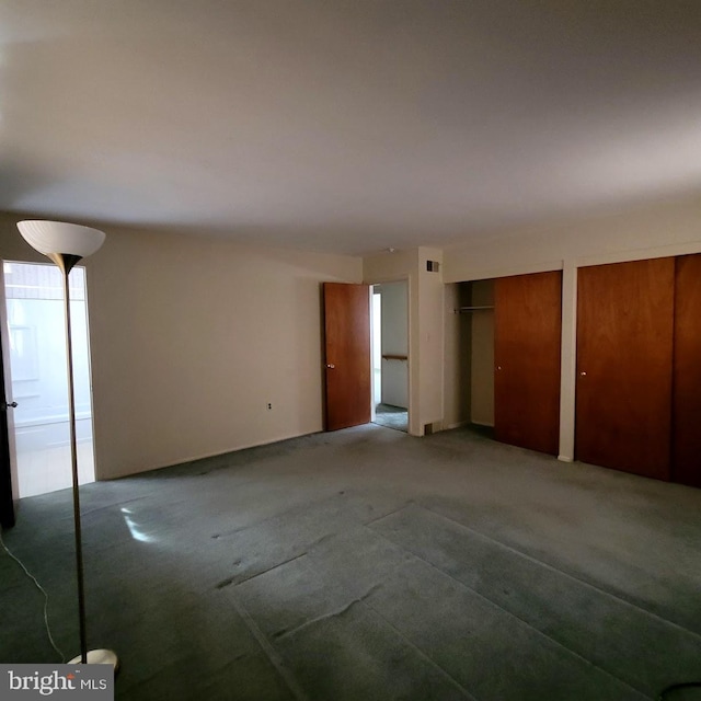 unfurnished bedroom featuring carpet flooring and two closets