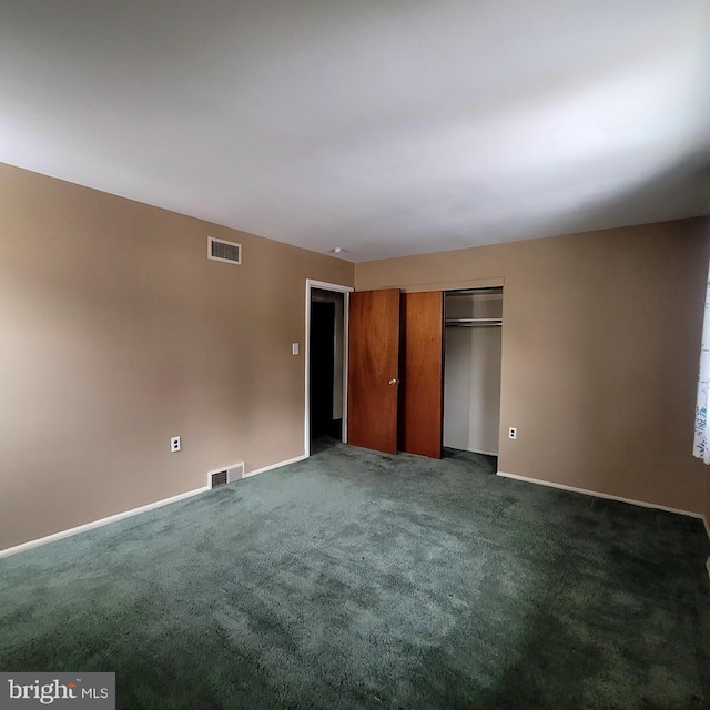 unfurnished bedroom with a closet and dark colored carpet