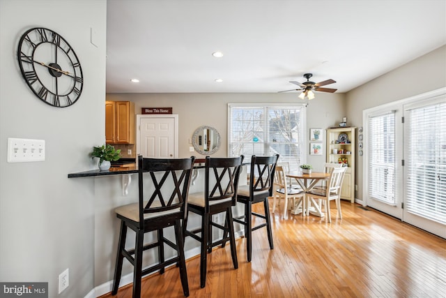 dining room featuring baseboards, recessed lighting, light wood-type flooring, and a healthy amount of sunlight