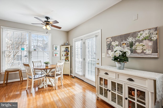 dining room featuring ceiling fan, light wood-type flooring, a wealth of natural light, and baseboards