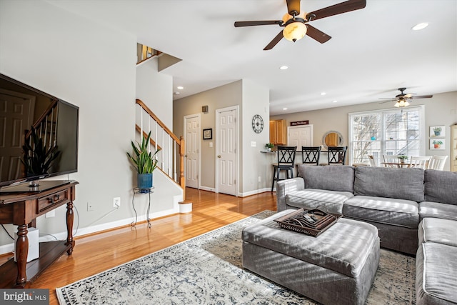 living room featuring baseboards, ceiling fan, wood finished floors, stairs, and recessed lighting