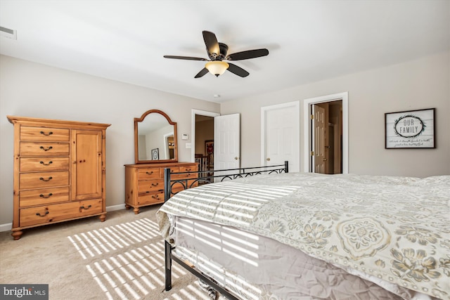 bedroom featuring baseboards, ceiling fan, visible vents, and light colored carpet