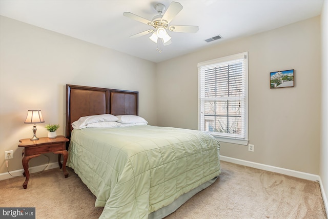 bedroom with light carpet, ceiling fan, visible vents, and baseboards