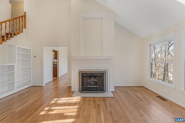 unfurnished living room featuring high vaulted ceiling and light hardwood / wood-style flooring