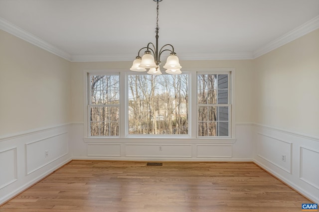 unfurnished dining area featuring an inviting chandelier, crown molding, and light hardwood / wood-style floors