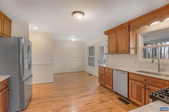 kitchen with stainless steel appliances, sink, and light hardwood / wood-style flooring