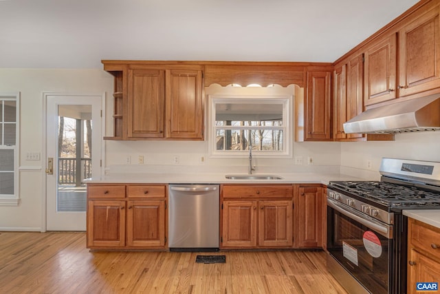 kitchen featuring stainless steel appliances, a healthy amount of sunlight, sink, and light wood-type flooring