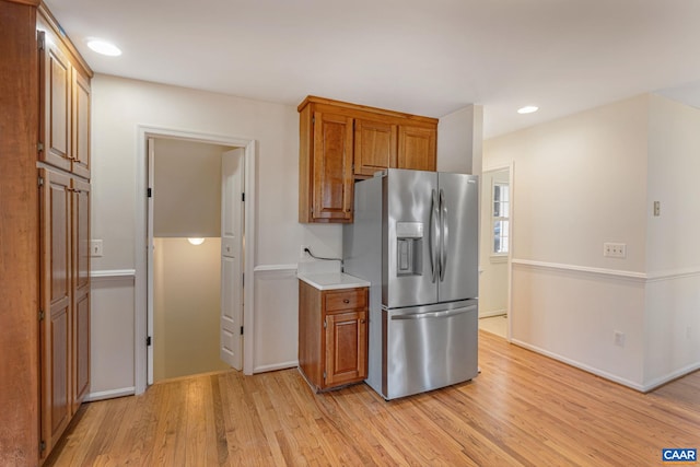 kitchen with stainless steel fridge with ice dispenser and light hardwood / wood-style floors