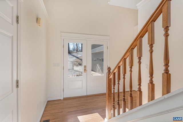 foyer entrance featuring wood-type flooring, ornamental molding, and french doors