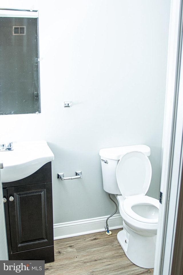 bathroom with hardwood / wood-style flooring, vanity, and toilet