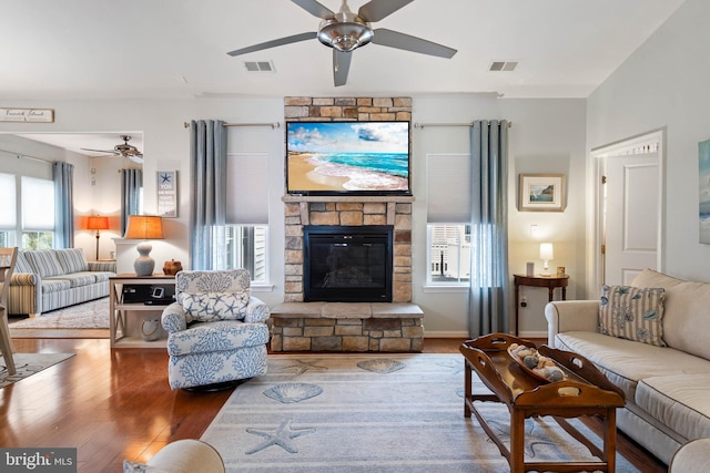 living room featuring hardwood / wood-style flooring, ceiling fan, and a fireplace