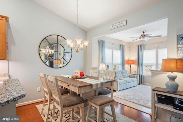 dining space featuring ceiling fan with notable chandelier and light hardwood / wood-style flooring