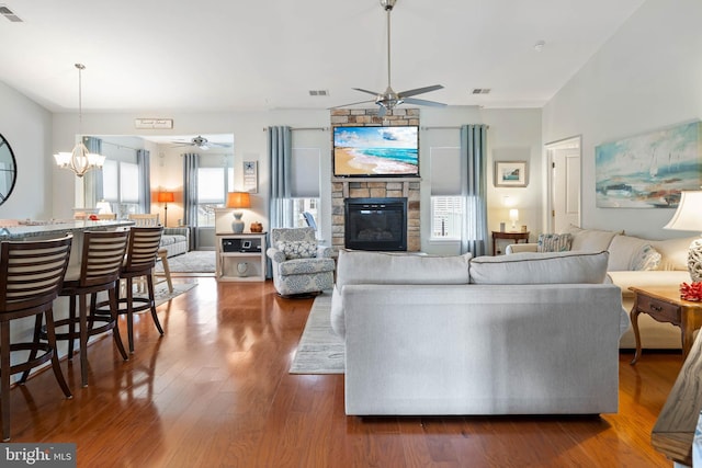 living room featuring ceiling fan with notable chandelier, a fireplace, and dark hardwood / wood-style floors