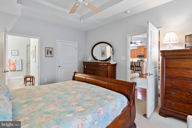 bedroom with light carpet, a tray ceiling, ornamental molding, and ceiling fan