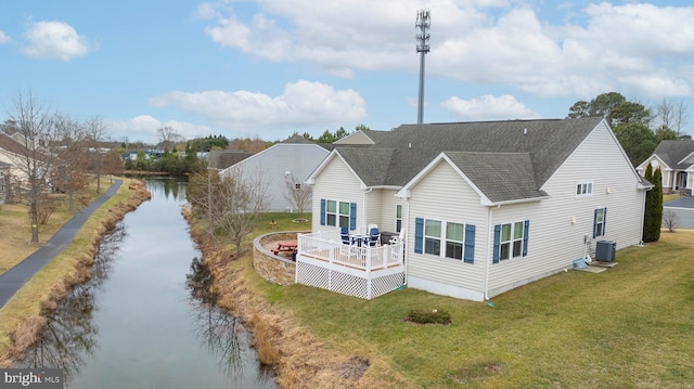 rear view of house with a deck with water view, a yard, central AC, and a fire pit