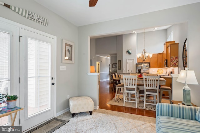 interior space with light tile patterned floors and ceiling fan with notable chandelier