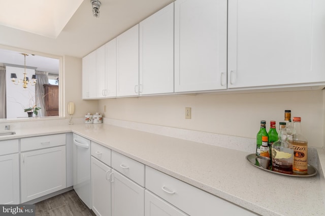 kitchen with white cabinetry, a chandelier, light stone countertops, and light wood-type flooring