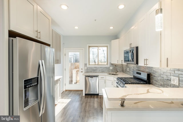 kitchen featuring stainless steel appliances, light stone countertops, sink, and white cabinets