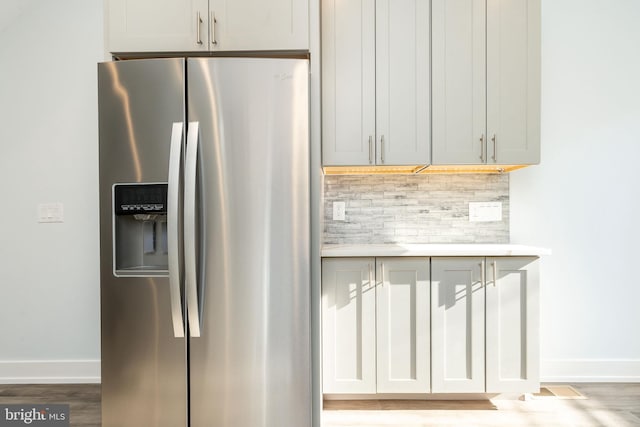 kitchen featuring wood-type flooring, decorative backsplash, and stainless steel fridge with ice dispenser