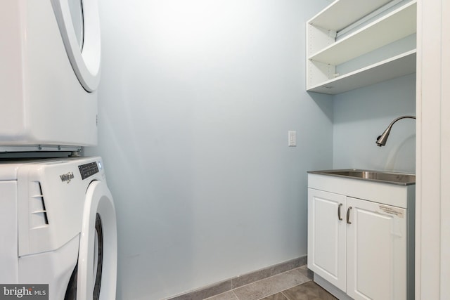 laundry room with stacked washer and dryer, cabinets, sink, and light tile patterned floors