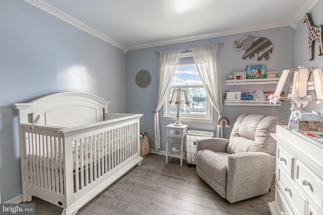 bedroom with hardwood / wood-style flooring, ornamental molding, and a crib