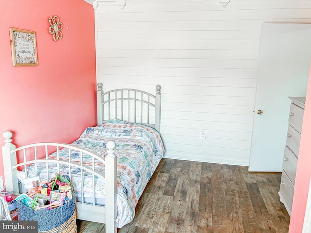 bedroom with dark hardwood / wood-style flooring and wood walls