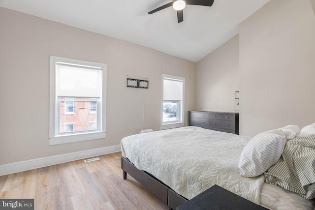 bedroom featuring multiple windows, vaulted ceiling, ceiling fan, and light hardwood / wood-style flooring