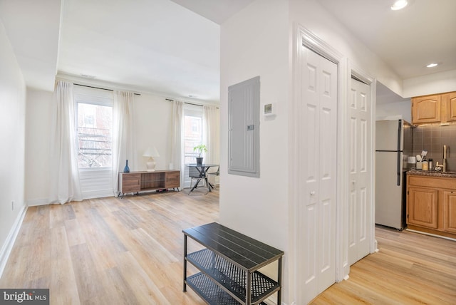 hallway with light hardwood / wood-style flooring and electric panel