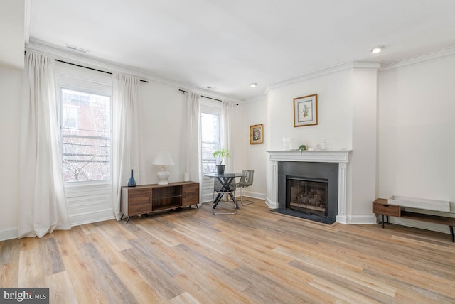 living area with plenty of natural light, ornamental molding, and light wood-type flooring