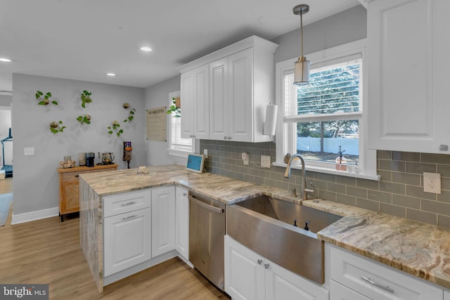 kitchen with stainless steel dishwasher, kitchen peninsula, sink, and white cabinets