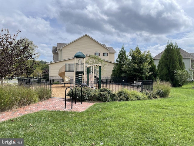 back of house with a playground and a lawn