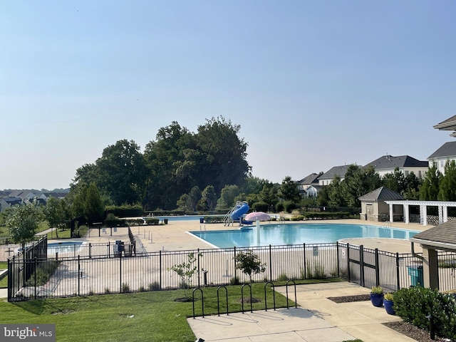 view of swimming pool with a water slide, a yard, and a patio area