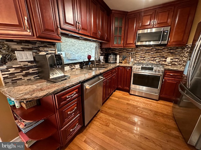 kitchen with tasteful backsplash, light hardwood / wood-style flooring, stainless steel appliances, and stone countertops