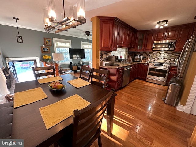 dining area featuring crown molding, ceiling fan with notable chandelier, sink, and hardwood / wood-style floors